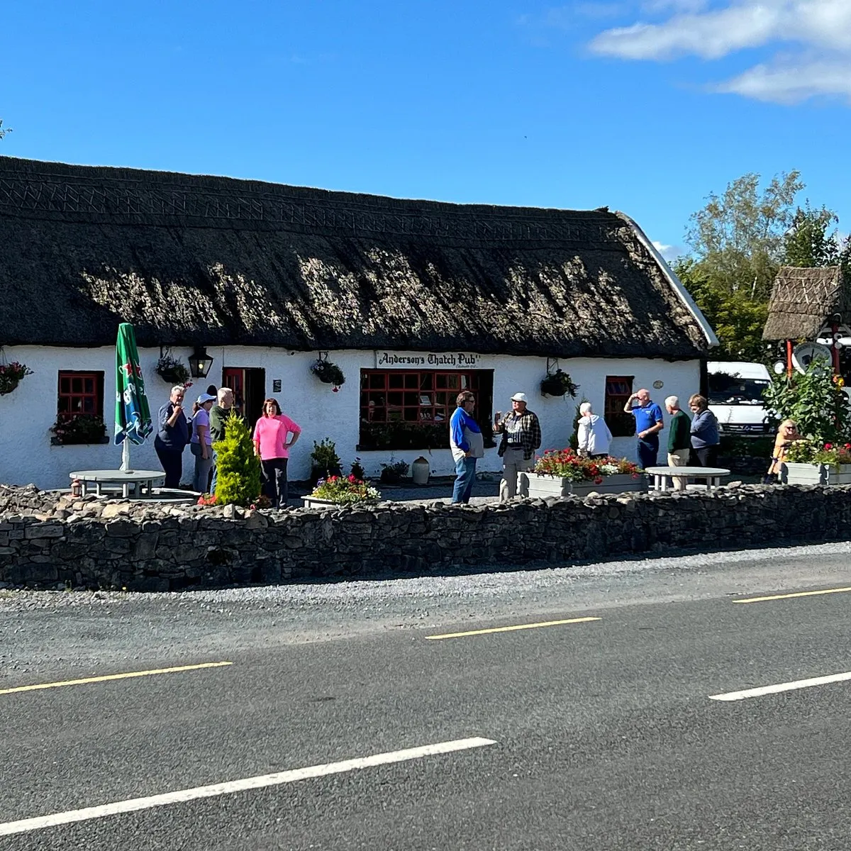 The thatched cottage exterior of Anderson's Thatch Pub, a whitewashed building with a traditional straw thatch roof